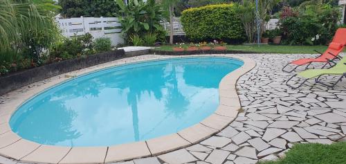 a swimming pool with a stone path around it at Chez Mimose et Henri in Saint-Benoît