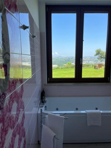 a bathroom with two windows and a bath tub with two white chairs at Mirabel in Chieti