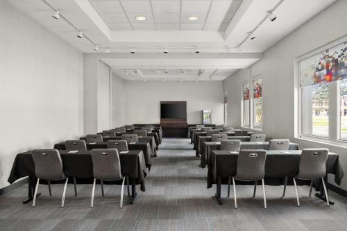 a conference room with tables and chairs and a screen at Aloft Chicago O'Hare in Rosemont