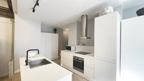 een witte keuken met witte kasten en een fornuis bij Unique 3 Bedroom Flat in Vibrant Frederiksberg in Kopenhagen
