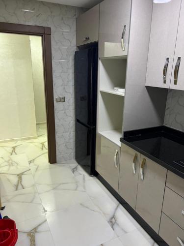 eine Küche mit weißen Fliesenböden und einem Spiegel in der Unterkunft Apartment Nador Jadid Hay Al Matar Appart 009 in Nador