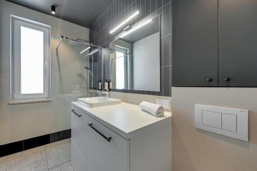 ein Badezimmer mit einem weißen Waschbecken und einem Spiegel in der Unterkunft Luxury Aura 40 - 6 by Grand Apartments in Danzig