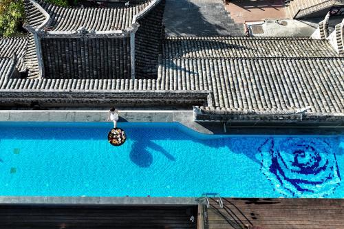 una persona in piedi in una piscina con una palla nell'acqua di Phoenix Hall House Hotel a Fenghuang