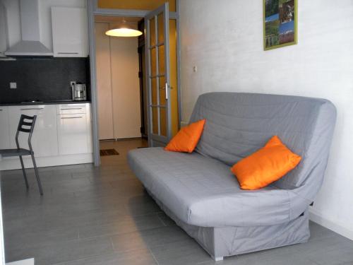 un canapé gris avec deux coussins orange dans une cuisine dans l'établissement Appartement 30m2 classé 2 étoiles Atout France 200m port plages commerces, à Saint-Cyprien