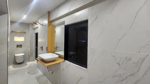a white bathroom with a sink and a toilet at Hotel Nova Bling in Rajkot