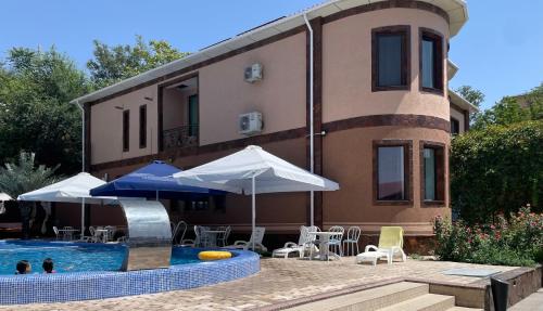 a house with a swimming pool with umbrellas and chairs at Вилла Эдем in Shymkent