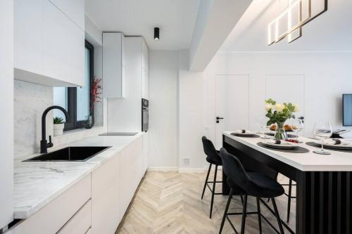 uma cozinha com armários brancos e uma mesa com cadeiras em Mellow - Calea Victoriei - 2BR Luxury Apartment em Bucareste