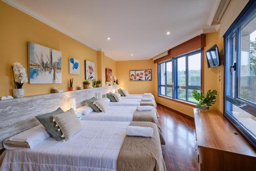 fila de camas en una habitación con ventanas en Peregrina Pensión 1, en O Pedrouzo