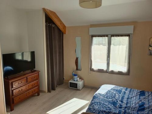une chambre avec un lit et une télévision à écran plat dans l'établissement Maison à côté de la mer, à Flamanville