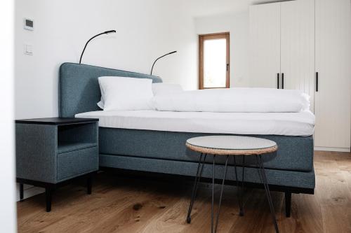 a bedroom with a bed with a stool and a table at Design Appartements Ehrenhausen in Ehrenhausen