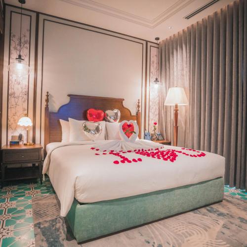 a bedroom with a large bed with red flowers on it at Regal Collection House in Dương Cảnh