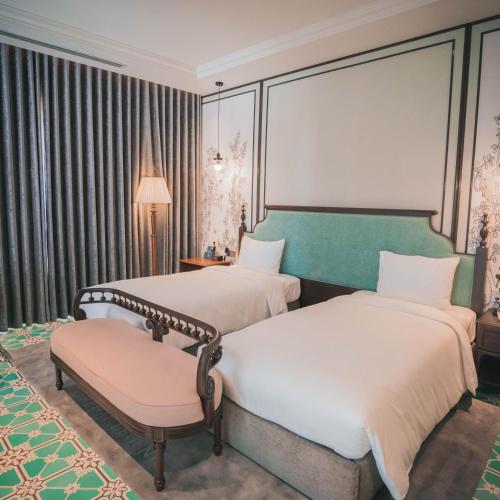 a hotel room with two beds and a chair at Regal Collection House in Dương Cảnh