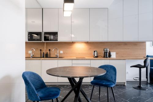 a kitchen with a wooden table and blue chairs at RentPlanet - Apartamenty OVO in Wrocław