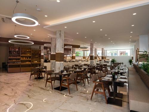 un restaurante con mesas y sillas en una habitación en Porto Greco Village Beach Hotel, en Hersonissos