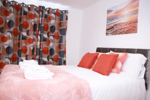 a bedroom with a bed with red and orange pillows at Kenton Cozy Apartment in Harrow