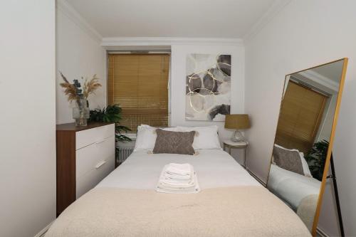 a small bedroom with a bed and a mirror at Bright & modern Islington 2BD apt for 6 in London