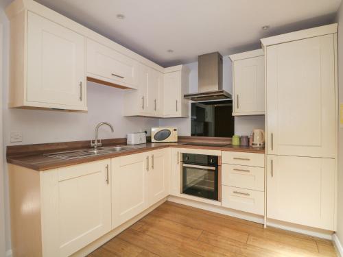 a white kitchen with white cabinets and a sink at Badgers Sett in Fareham