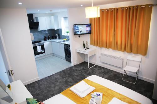 een woonkamer met een keuken met een oranje gordijn bij South Harrow Apartment in Londen