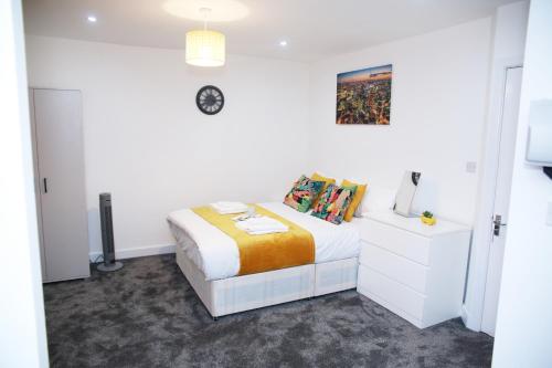 a white bedroom with a bed and a clock on the wall at South Harrow Apartment in London