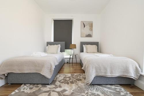 2 camas en una habitación con paredes blancas y alfombra en Stay in Islington in style 3BDR apt Nr Upper St en Londres