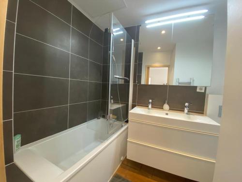 une salle de bain avec une baignoire, un lavabo et un miroir dans l'établissement Luminueux T3 au cœur de Biarritz, proche plages et Halles ! - FR-1-239-973, à Biarritz