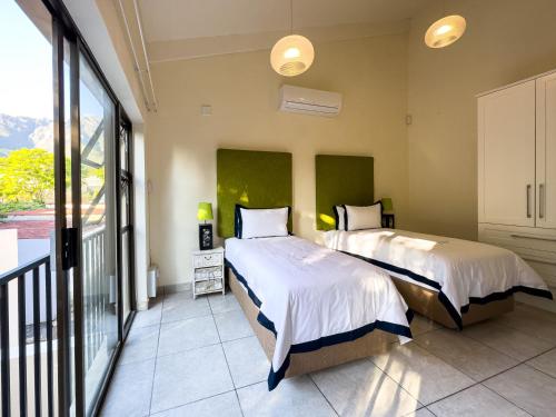 two beds in a room with a balcony at DE WET 5 FRANSCHHOEK in Franschhoek