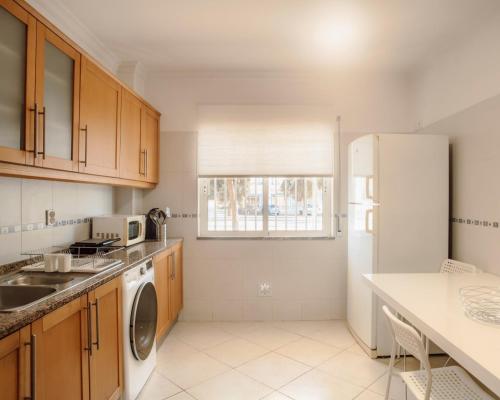 eine Küche mit Holzschränken und einem weißen Kühlschrank in der Unterkunft Harbours Way in Olhão