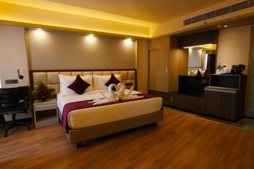 um quarto com uma cama grande e uma televisão em Fort Manor em Trivandrum