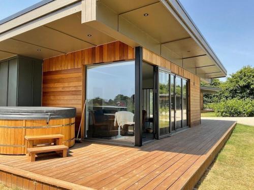 a house with a wooden deck with a hot tub at Stunning "Orwell" Scandinave Lodge with Private Hot Tub in East Bergholt