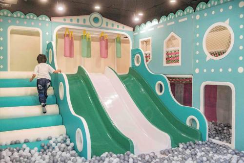 a child sliding down a slide in a play room at Golden Tulip - Aesthetics in Zhunan