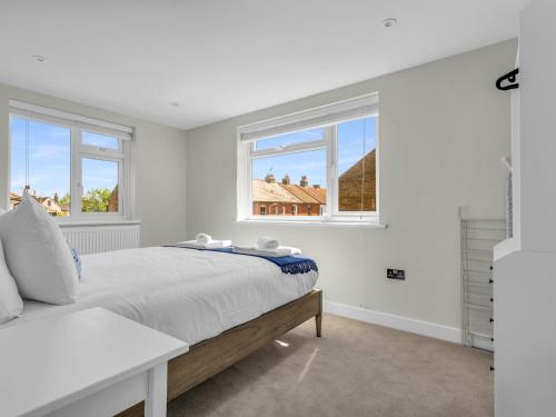 a white bedroom with a bed and two windows at Pass the Keys Flat 1 Elegance Meets Modern Luxury in Whitstable