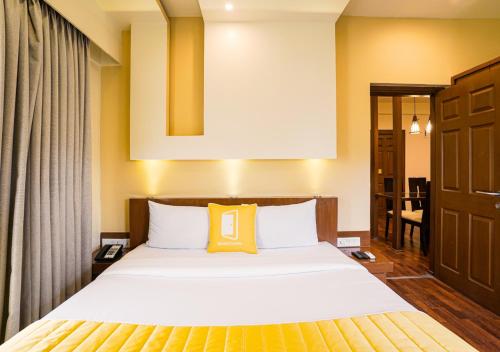 a bedroom with a bed with a yellow pillow on it at BloomSuites I Electronics City in Bengaluru