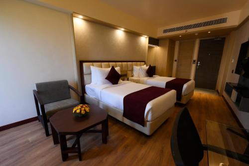 a hotel room with two beds and a chair at Fort Manor in Trivandrum