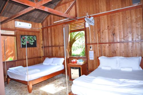 2 camas en una habitación con paredes de madera en Homestay Xóm Dừa Nước, en Ben Tre