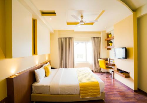 a hotel room with a bed and a desk at BloomSuites I Electronics City in Bengaluru