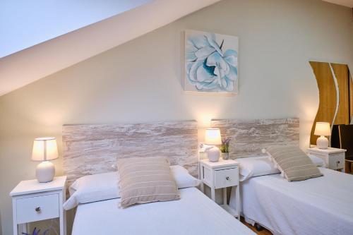 two beds in a room with two lamps on tables at Peregrina Pensión 2 in O Pedrouzo