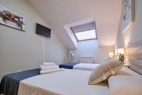 a attic bedroom with two beds and a window at Peregrina Pensión 2 in O Pedrouzo