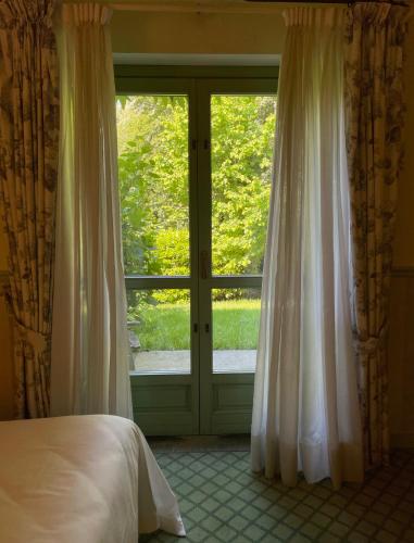 a bedroom with a bed and a large window at Locanda Maison Verte in Cantalupa