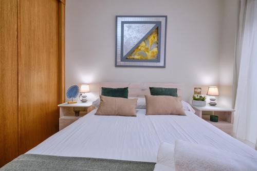 a bedroom with a large white bed with two tables at Peregrina Pensión 2 in O Pedrouzo
