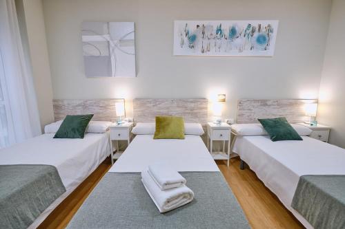 a room with two beds and two night stands at Peregrina Pensión 2 in O Pedrouzo