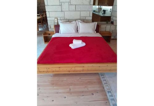 a bed with a red blanket on top of it at Tsarouxi village 1 in Karditsa