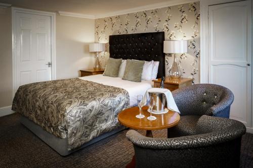 a hotel room with a bed and two chairs at The Bridge Hotel and Spa in Wetherby