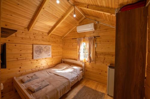 ein Schlafzimmer mit einem Bett in einer Holzhütte in der Unterkunft Via river in Podgorica