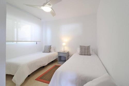 um quarto branco com 2 camas e uma janela em Modern apartment with pool on the beachfront in Marbella by SharingCo em Marbella