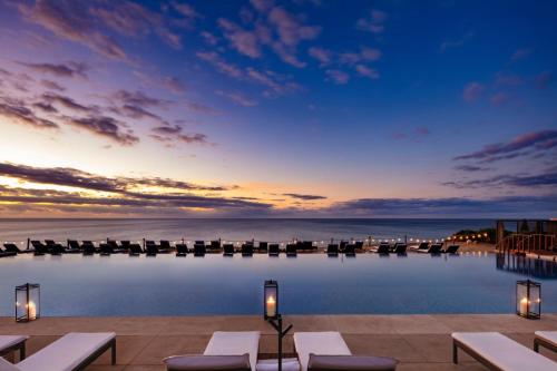 a resort pool with chairs and a view of the ocean at Casa Maat at JW Marriott Los Cabos Beach Resort & Spa in San José del Cabo