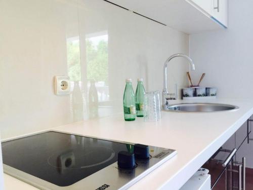 una cucina bianca con un lavandino e bottiglie su un bancone di Apartments Villa Klaudia - Adults Only a Crikvenica