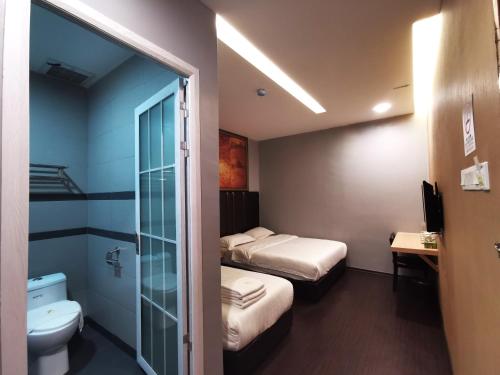 a small bathroom with two beds and a toilet at Zenz Hotel in Kulai