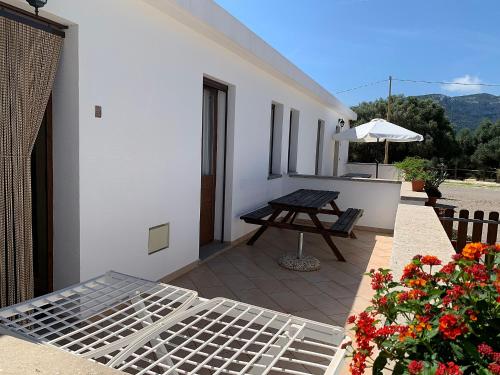 a patio with a table and a bench and flowers at Vistamare in Orosei
