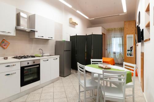 eine Küche mit weißen Schränken sowie einem Tisch und Stühlen in der Unterkunft Casa Vacanza Nibbio 26 in Sperlonga