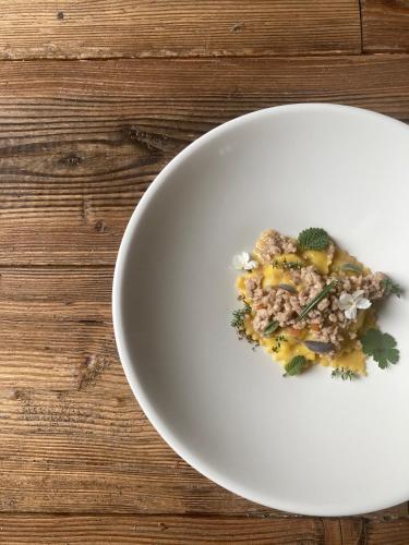 a white plate with food on a wooden table at Locanda Maison Verte in Cantalupa